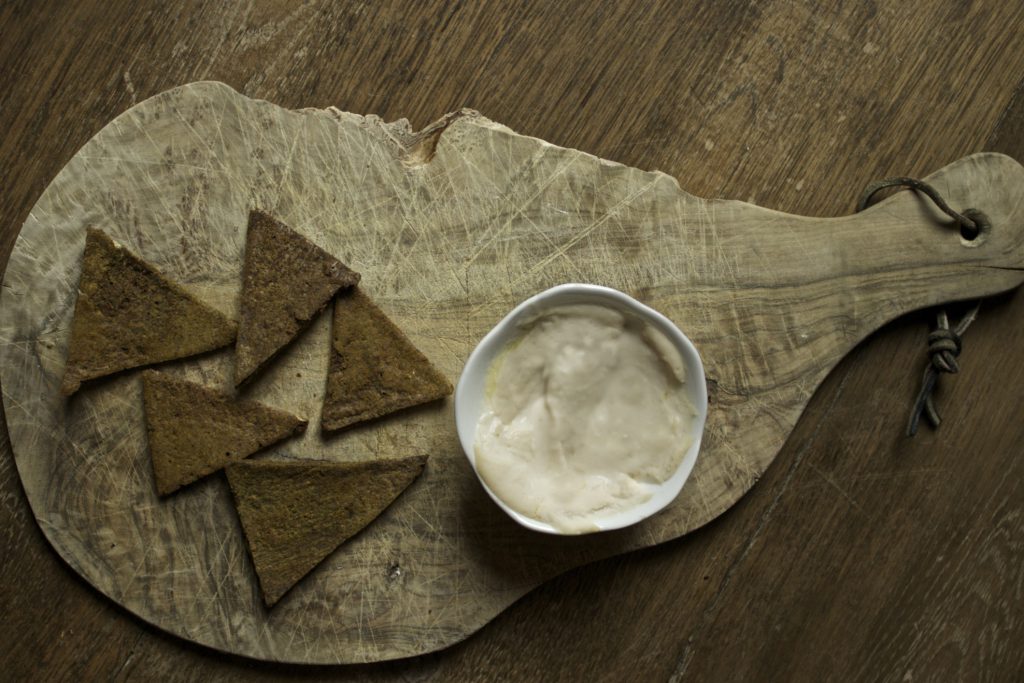 low histamine lentil crackers on an olive board with hummus