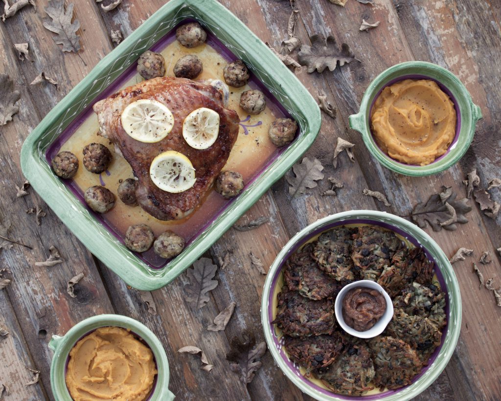 thanksgiving meal: turkey, jerusalem artichoke fritters, sweet potato mash, on a wood background surrounded with leaves