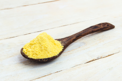 Asafoetida powder in wooden spoon on a white table