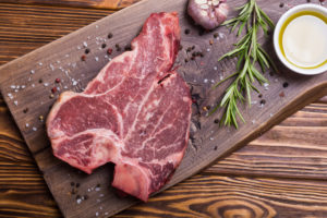 Raw beef steak T bone with ingredient . Porterhouse on cutting board .